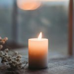 Candle burning in front of winter window. Photo by Sixteen Miles Out on Unsplash