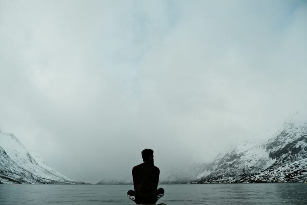 Person sitting in front of winter lake. Photo by Faris Mohammed on Unsplash