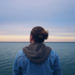 Person looking out toward the horizon of the ocean. Photo by Gray on Unsplash