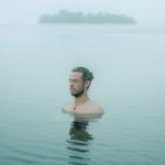 Person resting in calm water with eyes closed. Photo by Isaac Burke on Unsplash