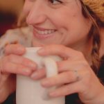 Woman smiling and holding mug of tea in her hands. Photo by Dayne Topkin on Unsplash