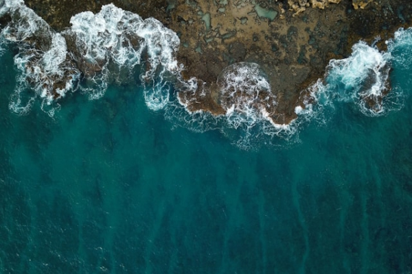 Waves crashing on rocks from overhead. Photo by Michael Olsen on Unsplash
