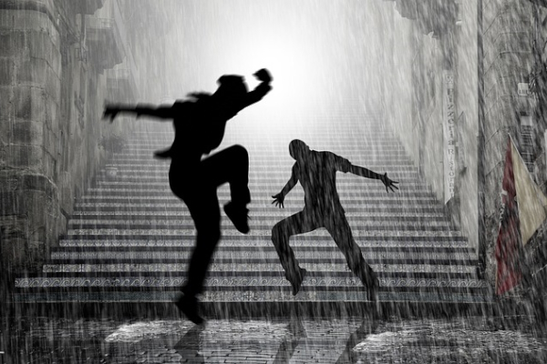 Two figures dancing in a downpour in front of city steps. Photo by Hansuan Fabregas on Pixabay