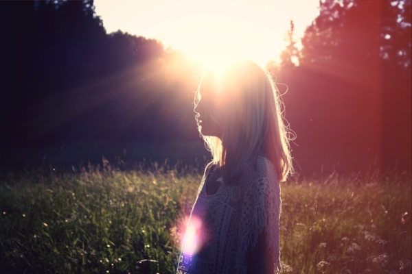Person with sunlight behind and flare at heart center. Photo by Julia Caesar on Unsplash.