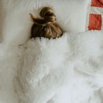 Person in bed with most of head covered by blanket. Photo by Kelly Sikkema on Unsplash.