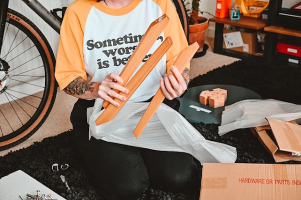 Person holding parts of wooden furniture to assemble wearing shirt, "Sometimes, worse is better." Photo by Nik on Unsplash