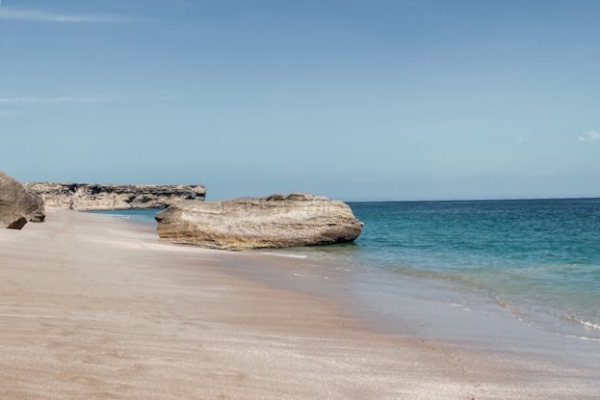 Sandy beach with large rock outcroppings. Photo by Ievgeniia Ghiglione