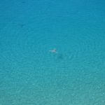 Person floating in a vast expanse of ocean. Photo by Jonny Clow