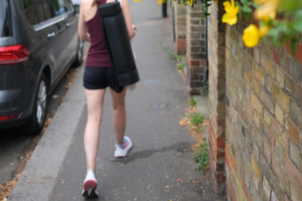 Person with yoga mat walking quickly down the sidewalk. Photo by Shoeib Abolhassani